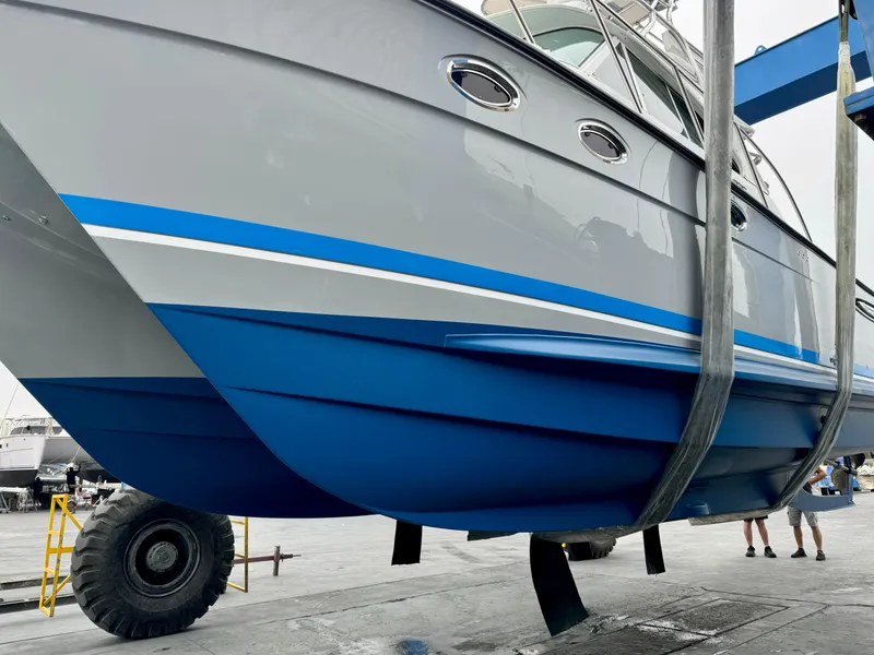 Slide: The Image of 2006 Glacier Bay 3480 Ocean Runner boat in dry dock, showcasing sleek blue and gray hull design. - 9