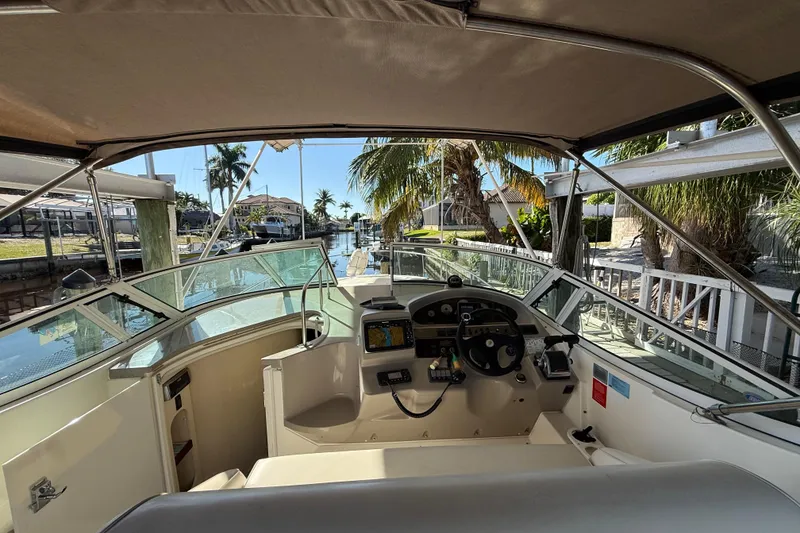 Slide: The Image of 2003 Cruisers Yachts 3075 Express cockpit with steering wheel, docked near palm trees. - 13