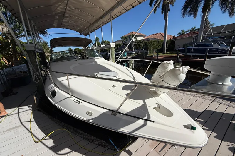 Slide: The Image of 2003 Cruisers Yachts 3075 Express docked under canopy with palm trees in background. - 2