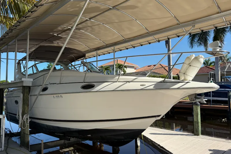 Slide: The Image of 2003 Cruisers Yachts 3075 Express under canopy, docked in sunny marina setting. - 3