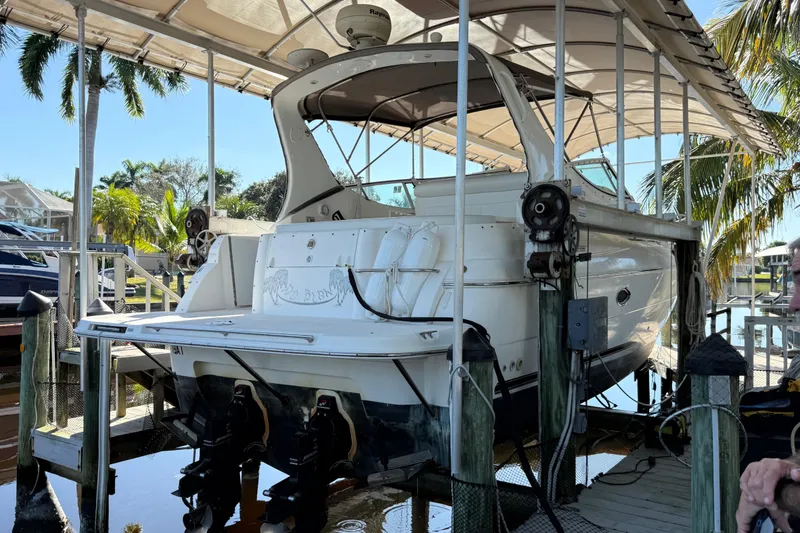 Slide: The Image of 2003 Cruisers Yachts 3075 Express docked under a canopy with palm trees. - 4