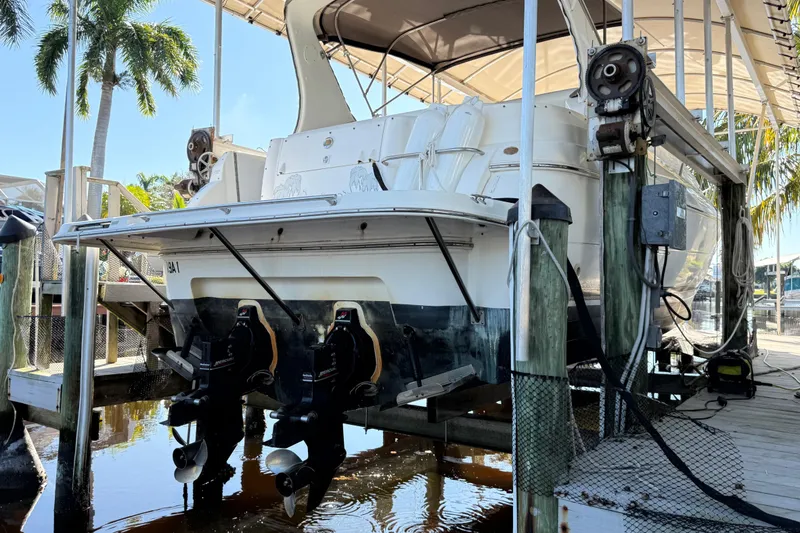 Slide: The Image of 2003 Cruisers Yachts 3075 Express on lift, docked near palm trees. - 5