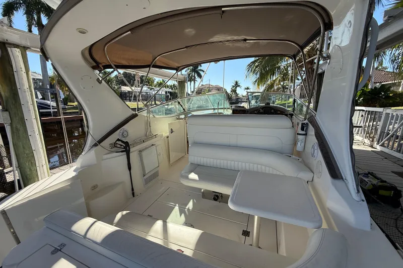 Slide: The Image of 2003 Cruisers Yachts 3075 Express interior with seating and table, docked near palm trees. - 8