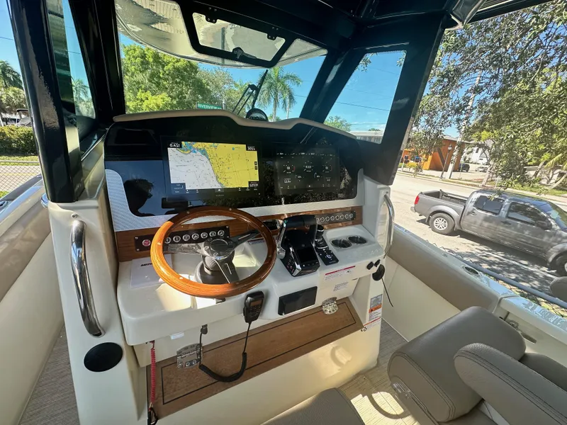 Slide: The Image of 2024 Chris-Craft Catalina 30 helm with navigation screens and wooden steering wheel. - 11