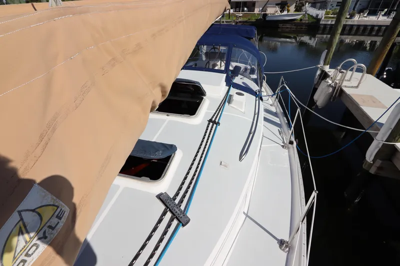 Slide: The Image of 1995 Nonsuch 260 sailboat docked, featuring tan sail cover and sleek deck design. - 10
