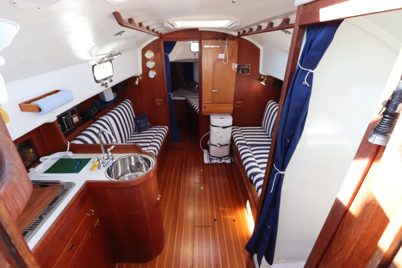 Slide: The Image of Interior of a 1995 Nonsuch 260 sailboat with striped seating and wooden finishes. - 22