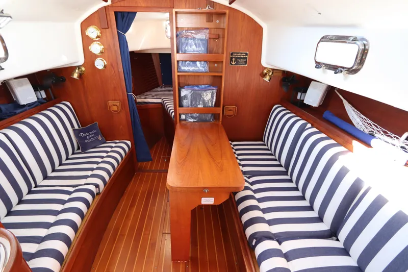Slide: The Image of Interior of a 1995 Nonsuch 260 sailboat with striped seating and wooden finishes. - 31