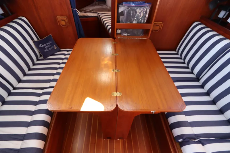 Slide: The Image of Interior of 1995 Nonsuch 260 sailboat with striped seating and wooden table. - 32