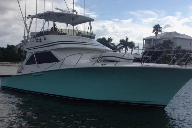 The Image of 1991 Spectrum 48 Convertible yacht on water, with palm trees and house in background. - 0