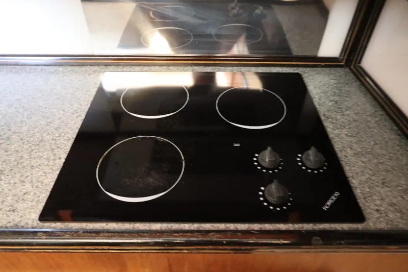 Slide: The Image of Black glass cooktop with four burners and control knobs on a granite countertop. - 23