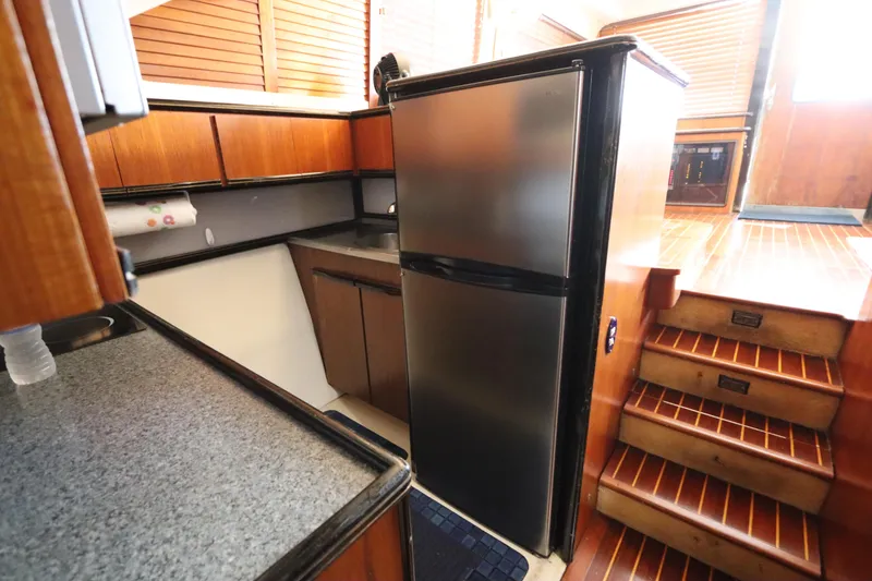 Slide: The Image of 1991 Spectrum 48 Convertible yacht kitchen with wood cabinets and stainless steel fridge. - 25