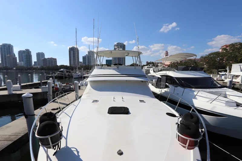 Slide: The Image of 1991 Spectrum 48 Convertible yacht docked in marina with city skyline backdrop. - 7