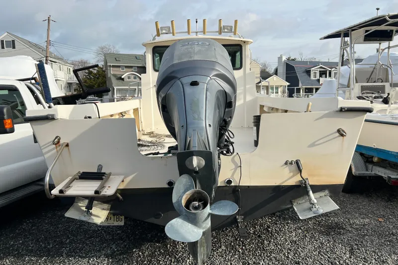 Slide: The Image of 2001 Parker 2520 Deep Vee Sport Cabin boat with outboard motor, parked on gravel. - 2