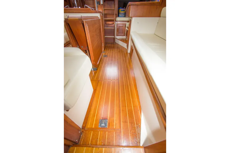 Slide: The Image of Interior of 1992 Pacific Seacraft Cutter with polished wood flooring and cushioned seating. - 26