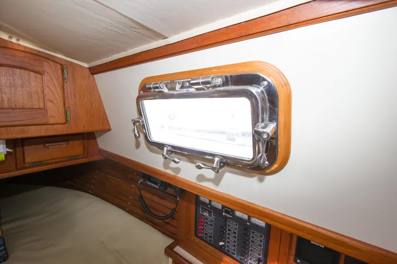 Slide: The Image of Interior of 1992 Pacific Seacraft Cutter, featuring a porthole and wooden cabinetry. - 27
