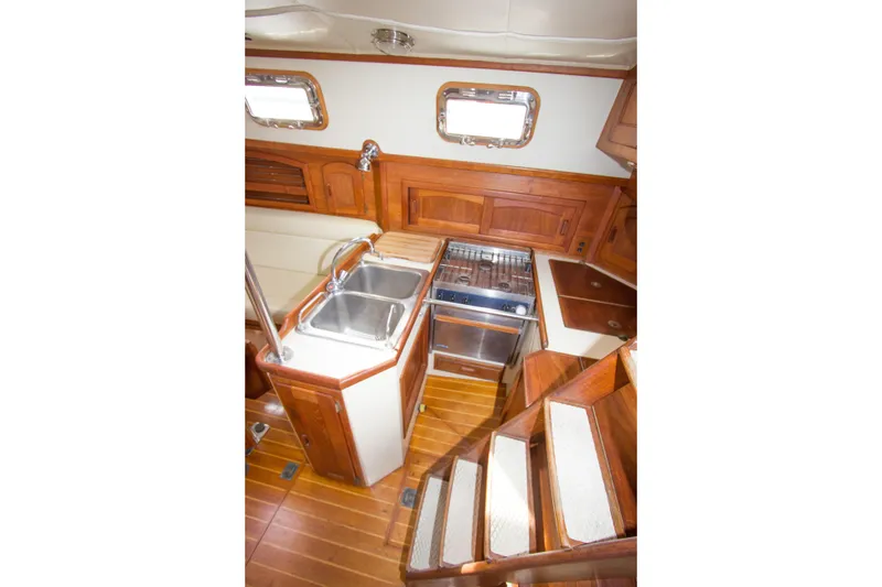 Slide: The Image of Interior of 1992 Pacific Seacraft Cutter, featuring wooden cabinetry and compact kitchen area. - 20