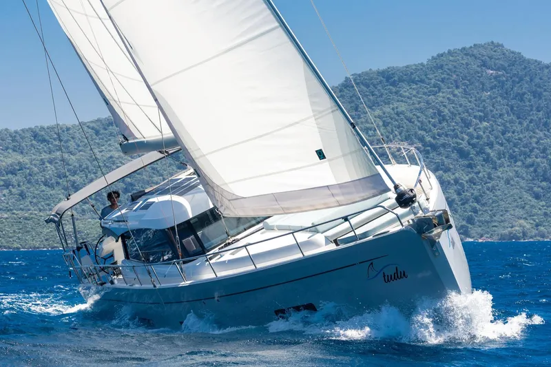 Slide: The Image of Sailing yacht Moody 48 deck saloon 2026 navigating through blue waters near lush green hills. - 10
