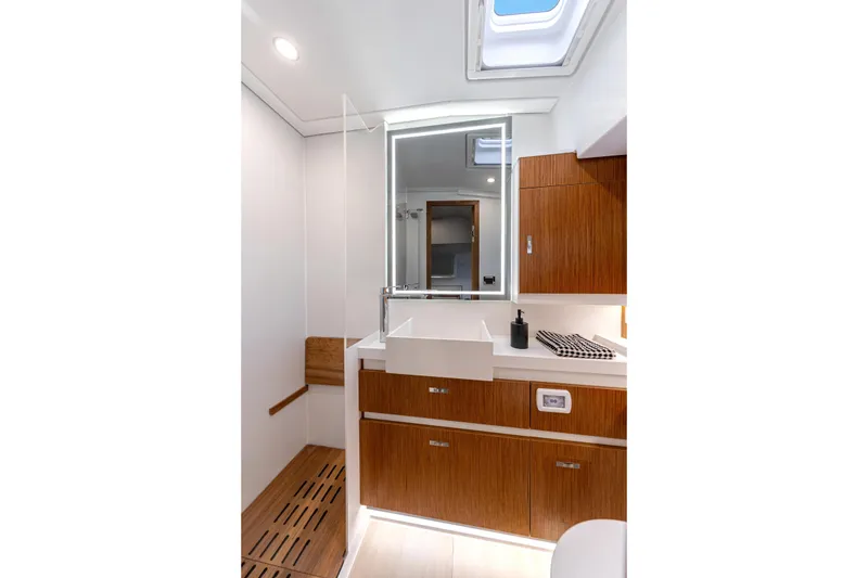 Slide: The Image of Modern bathroom interior on 2026 Moody 48 Deck Saloon yacht, featuring wood cabinetry and skylight. - 31