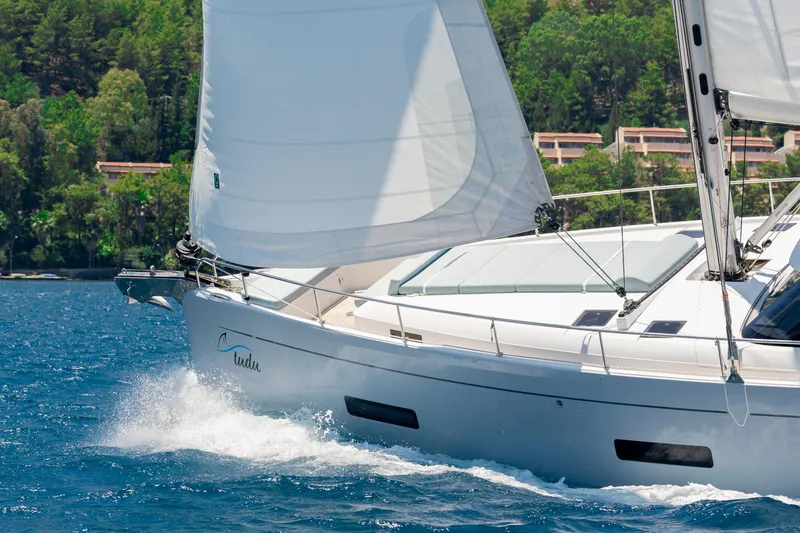 Slide: The Image of Sailing yacht Moody 48 deck saloon 2026 gliding on blue water near lush coastline. - 5