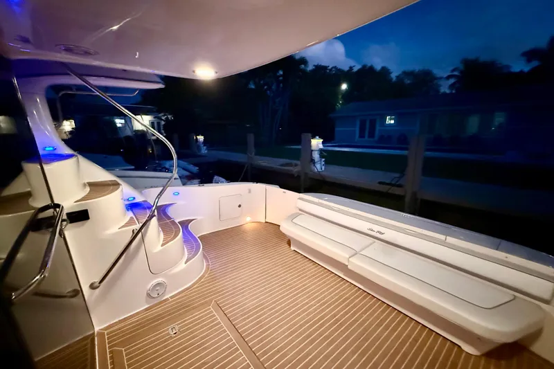 Slide: The Image of 1999 Sea Ray 560 Sedan Bridge yacht deck with elegant lighting and seating at dusk. - 19