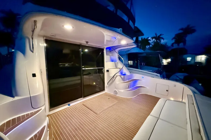 Slide: The Image of 1999 Sea Ray 560 Sedan Bridge yacht deck illuminated at night, featuring sleek design and ambient lighting. - 20