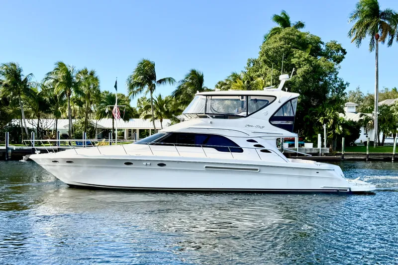 Slide: The Image of 1999 Sea Ray 560 Sedan Bridge yacht cruising on a sunny day, surrounded by palm trees. - 21