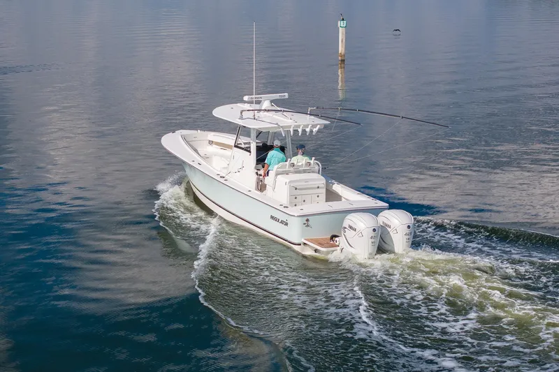 Slide: The Image of 2021 Regulator 31 boat cruising on calm water with dual Yamaha engines. - 10