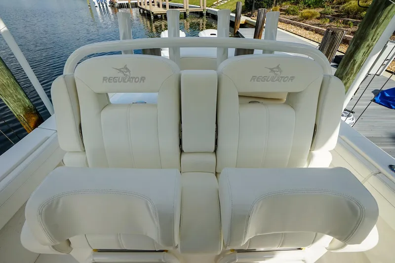 Slide: The Image of 2021 Regulator 31 boat seating with white upholstery at a dockside location. - 16
