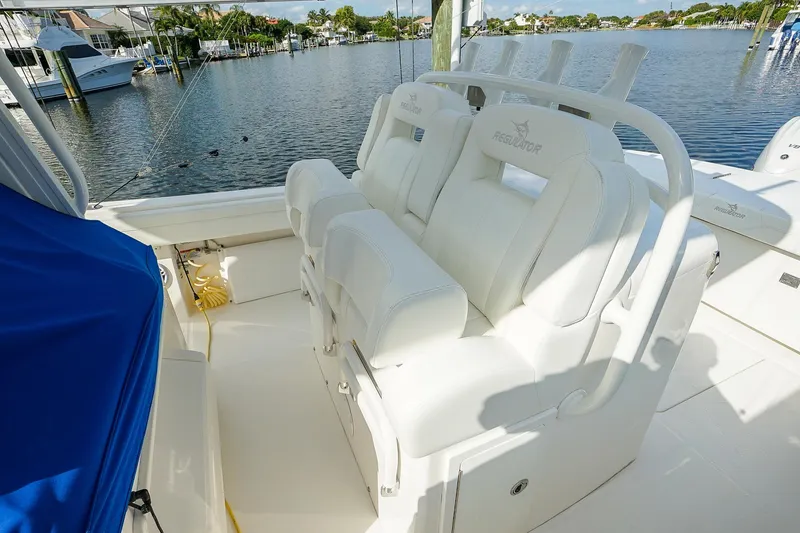 Slide: The Image of 2021 Regulator 31 boat with white seating, docked by a serene waterfront. - 17