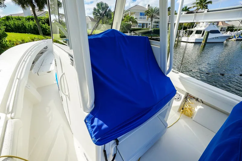 Slide: The Image of 2021 Regulator 31 boat interior with blue seat cover, docked by waterfront homes. - 19
