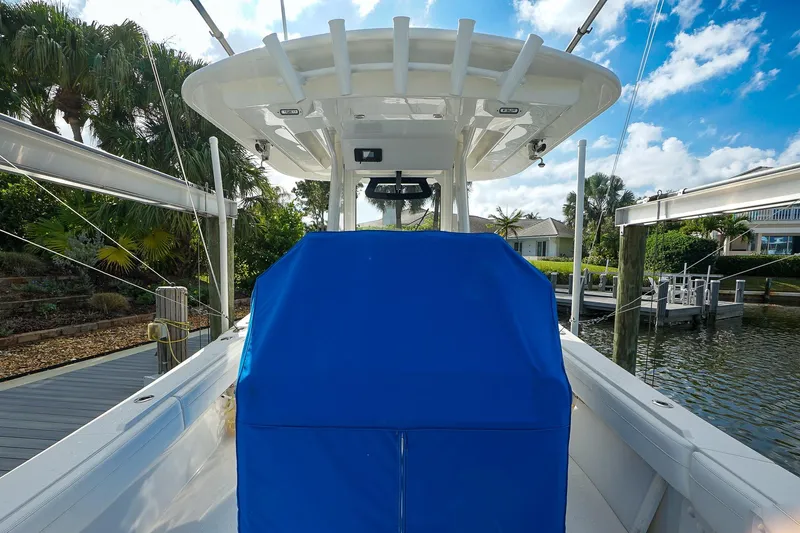 Slide: The Image of 2021 Regulator 31 boat with blue cover, docked near lush greenery and waterway. - 21