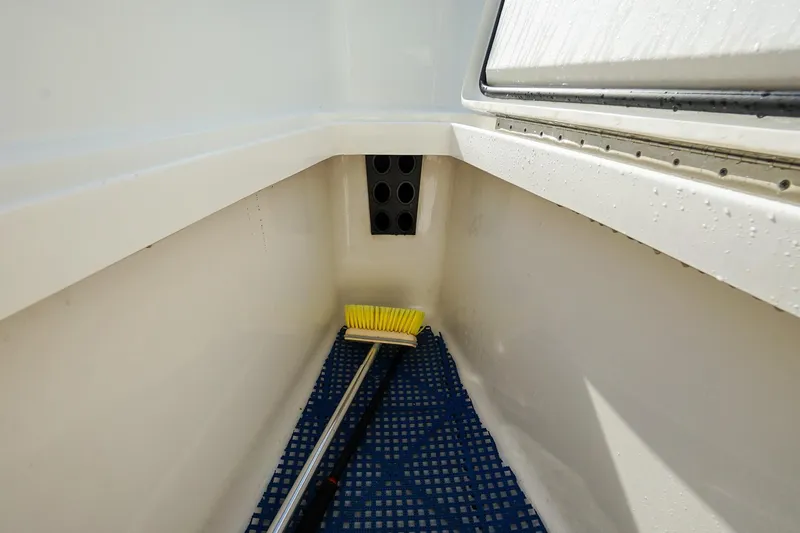 Slide: The Image of 2021 Regulator 31 boat storage compartment with cleaning brush and blue mat. - 22