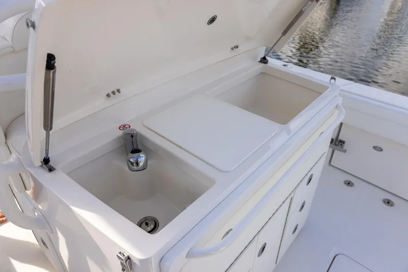 Slide: The Image of 2021 Regulator 31 boat sink and storage area with open lid, dockside view. - 43