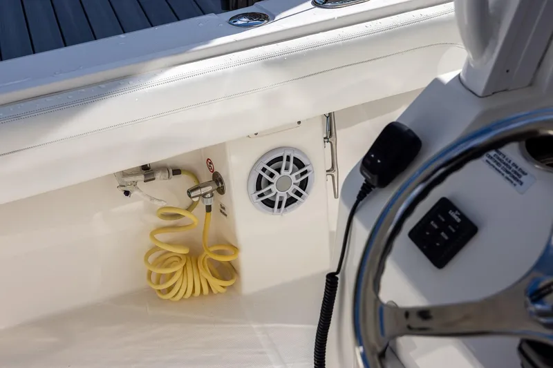 Slide: The Image of 2021 Regulator 31 boat interior with steering wheel, speaker, and coiled yellow hose. - 47