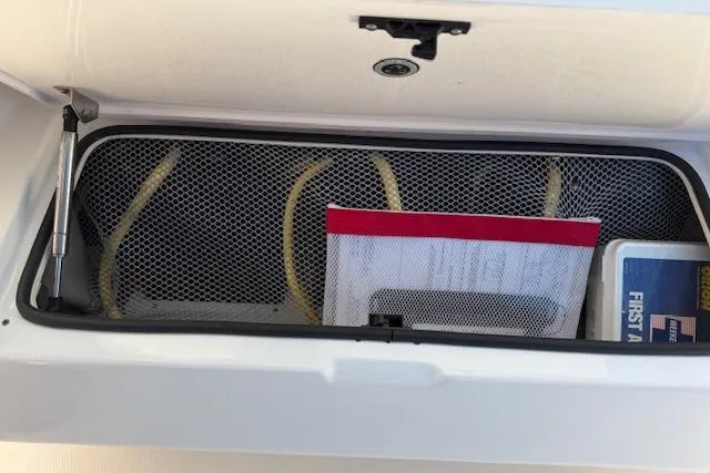 Slide: The Image of Storage compartment in a 2021 Regulator 31 boat with first aid kit and mesh netting. - 58