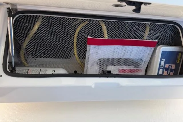 Slide: The Image of Open storage compartment on 2021 Regulator 31 boat with first aid kit and safety equipment. - 59