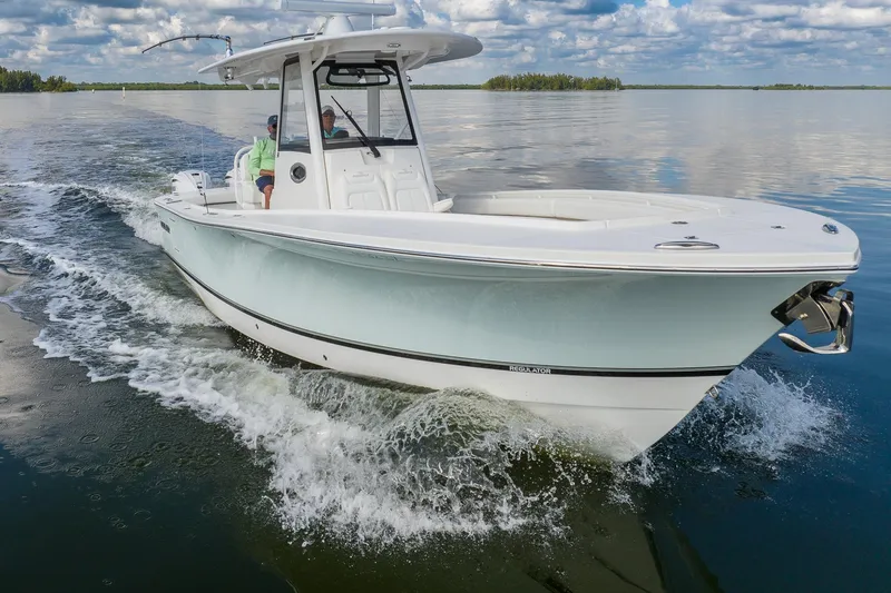 Slide: The Image of 2021 Regulator 31 boat cruising on calm water under a partly cloudy sky. - 6