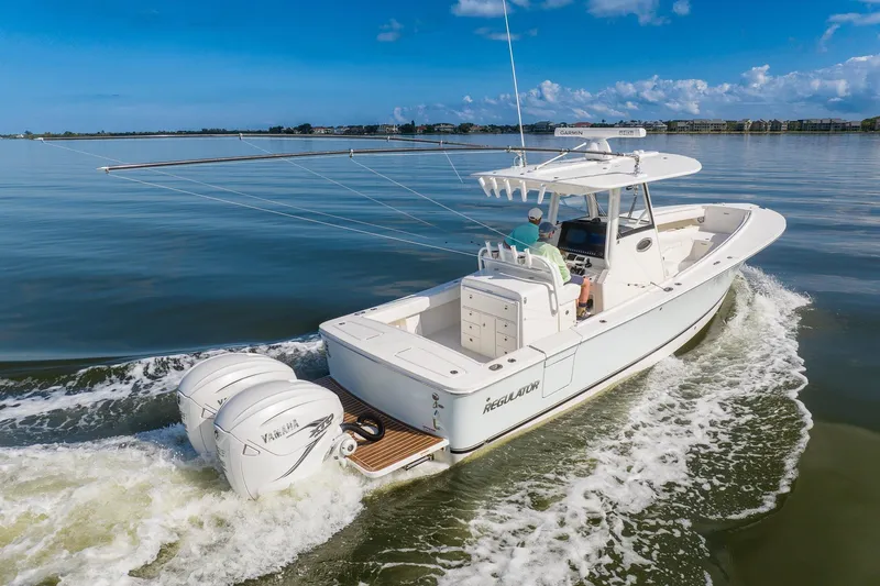Slide: The Image of 2021 Regulator 31 boat cruising on calm waters under a clear blue sky. - 8