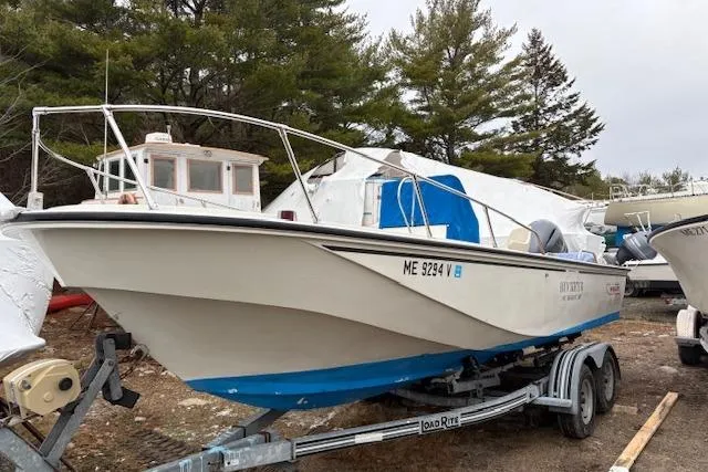 Slide: The Image of 1984 Boston Whaler Outrage 22 boat on trailer, parked outdoors with trees in background. - 4