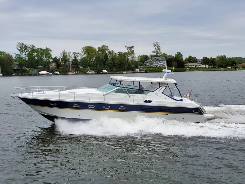 Slide: The Image of Giorgi 46 yacht cruising on a lake, 1993 model, surrounded by trees and houses. - 0