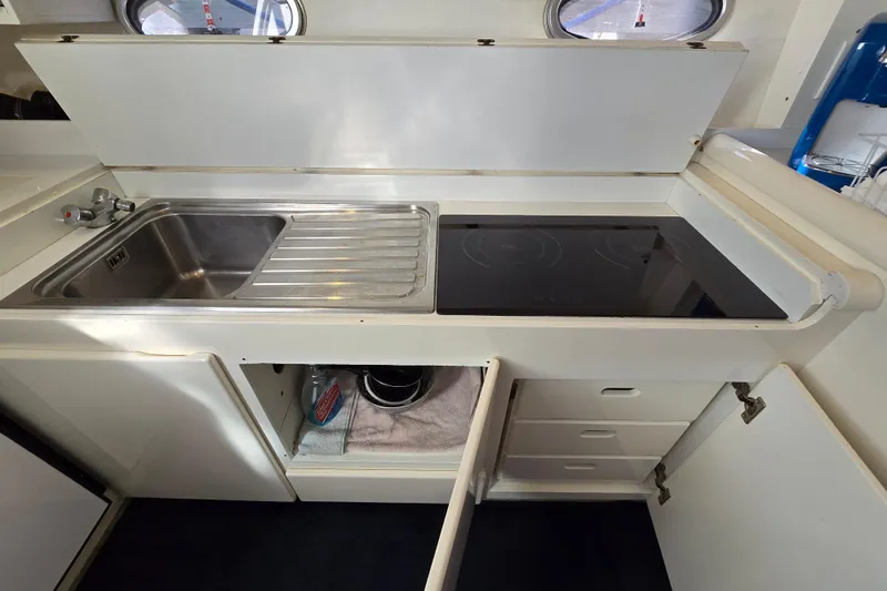 Slide: The Image of Compact kitchen area in a 1993 Giorgi 46 boat with sink and electric stove. - 103