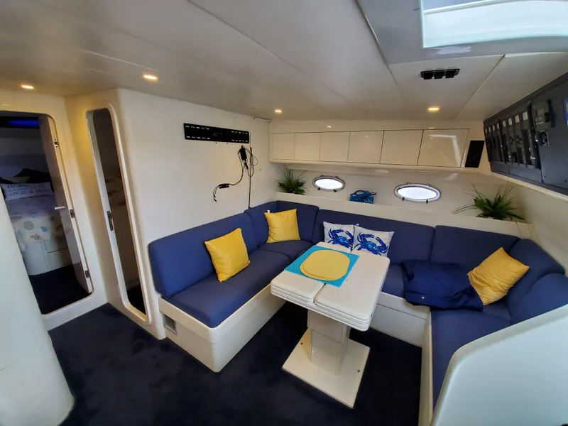 Slide: The Image of Luxurious Giorgi 46 yacht interior, featuring blue and yellow seating, dining table, and porthole windows. - 18