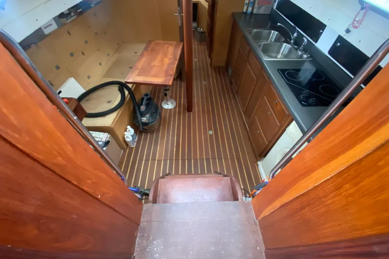 Slide: The Image of Interior of a 1966 Vanguard Bermudian Sloop with wooden cabinetry and modern kitchen amenities. - 8