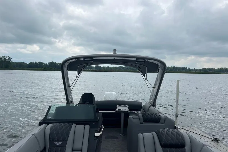 Slide: The Image of 2026 Bennington RX 25 RXFBA pontoon boat on a lake under cloudy skies. - 2