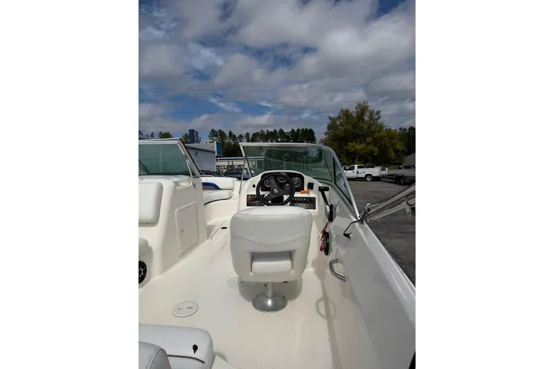 Slide: The Image of 2012 Hurricane SunDeck 187 OB boat interior with steering wheel and seating under cloudy sky. - 9