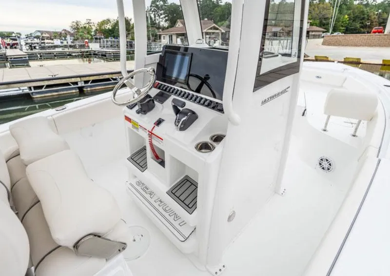 Slide: The Image of Manufacturer Provided Image: 2026 Sea Hunt Ultra 245 SE boat interior with modern helm and seating at a marina. - 3
