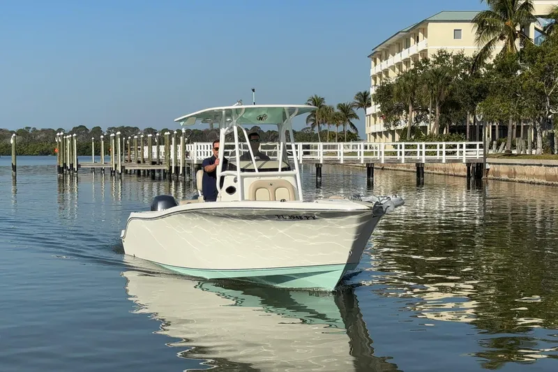 Slide: The Image of 2015 NauticStar 2500XS Offshore boat cruising near a dockside resort. - 1