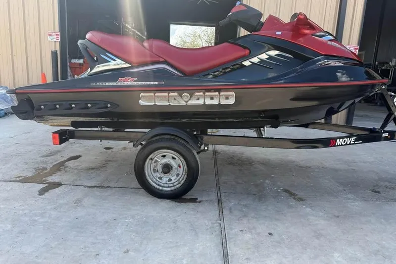 The Image of 2008 Seadoo RXT jet ski on trailer, black and red design, parked outside. - 1