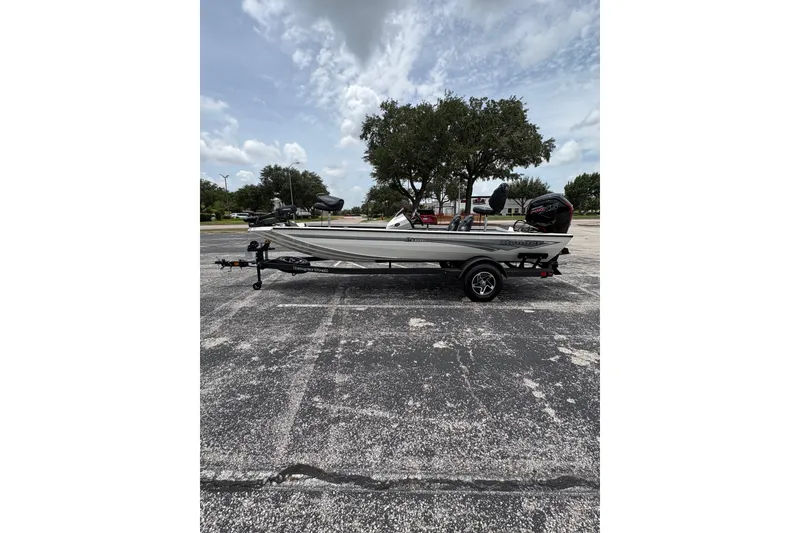 Slide: The Image of 2026 Ranger RT188C boat parked on asphalt, under a cloudy sky with trees in the background. - 7