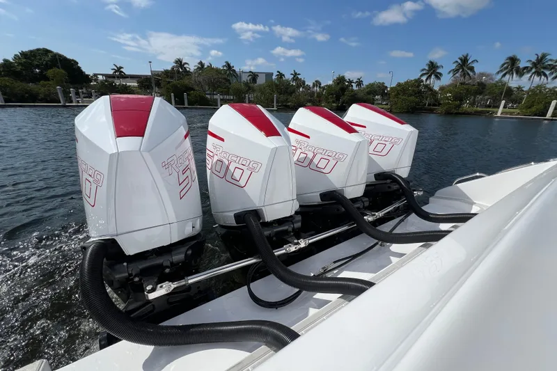 Slide: The Image of Four powerful outboard engines on a 2025 Cigarette 41 Nighthawk boat, docked by palm trees. - 17